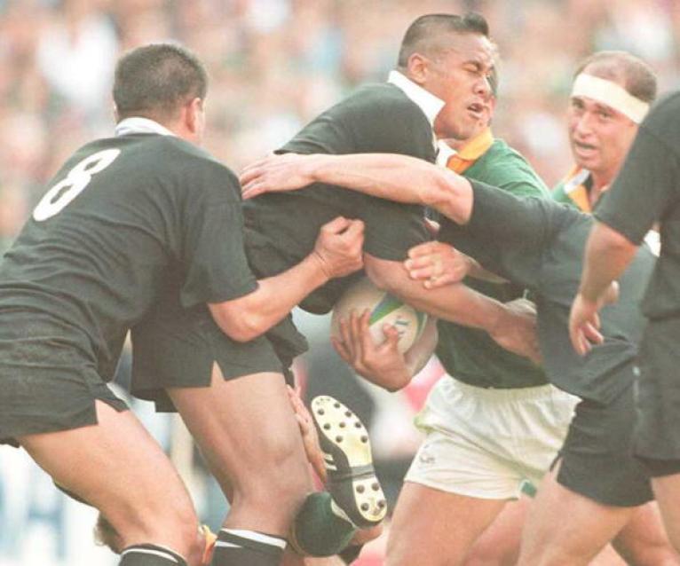 New Zealand winger Jonah Lomu (C) strains to get t